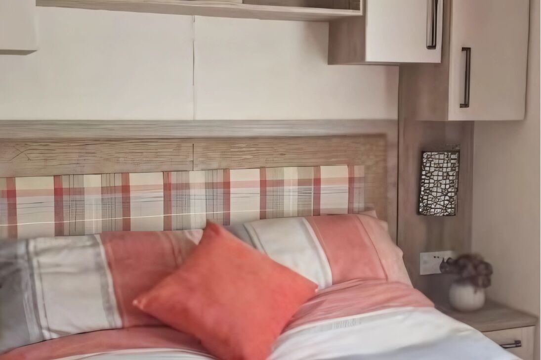 A bedroom with a bed, a nightstand, and a wall-mounted shelf.