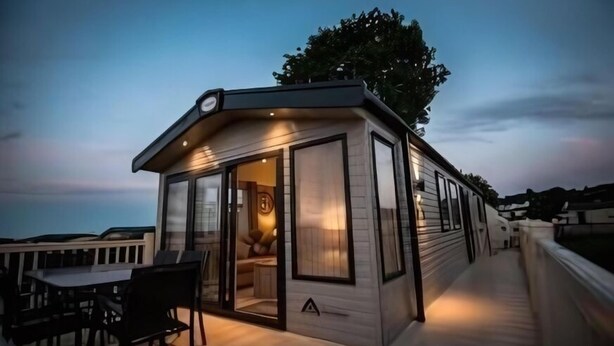 Una casa móvil moderna de un piso con terraza y zona de comedor.