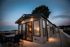 A modern, single-story mobile home with a deck and a dining area. - Sandytoes Holidays (Paignton)