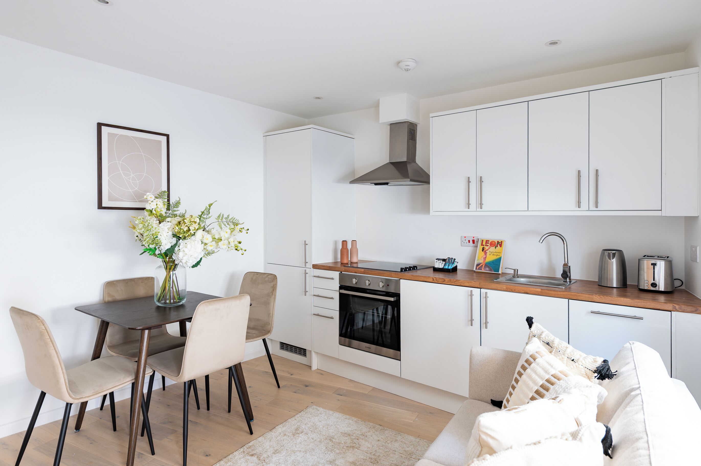 A modern kitchen with white cabinets, a wooden countertop, and a built-in oven.