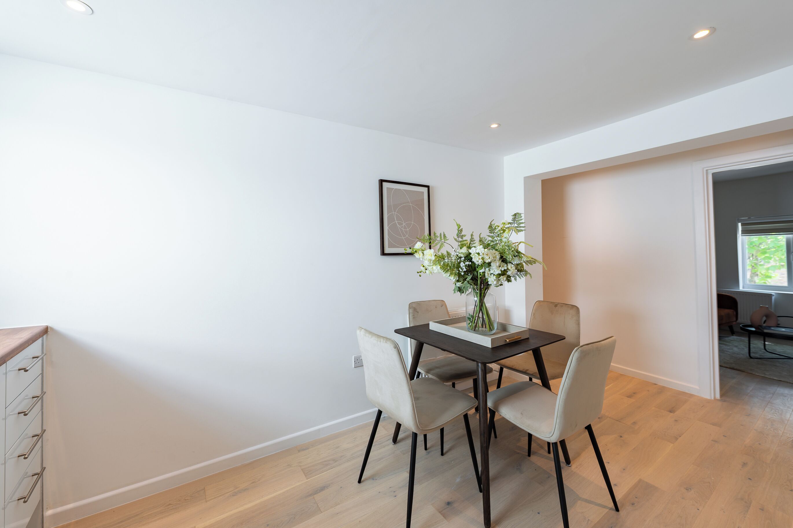 A dining area with a table, chairs, and a vase of flowers.