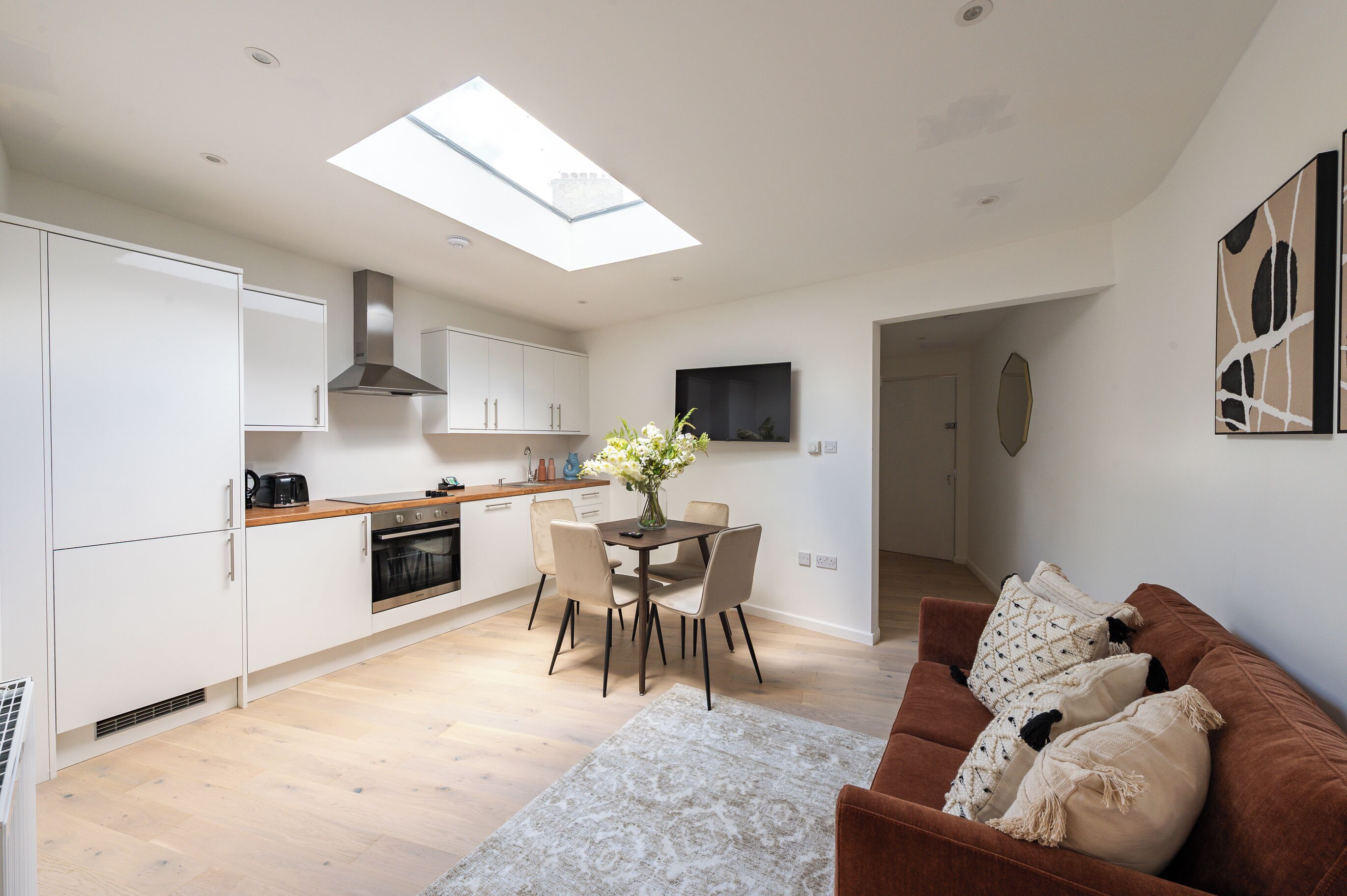 A modern kitchen with white cabinets, a central island, and a skylight.