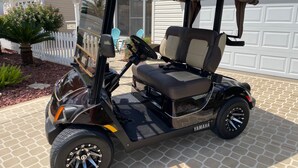 A golf cart parked in front of a house with a garage. - Modern charm meets vibrant living with outdoor oasis and golf cart fun! (The Villages)