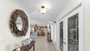 Un couloir agrémenté d’un miroir décoratif, d’une console en bois et, au fond, une cuisine moderne.