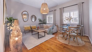 A modern living room with a sofa, coffee table, and dining table set. - Green Oaks Apartment in Tamboerskloof (Cape Town)