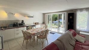 Une cuisine compacte avec une table et des chaises, un canapé rouge et une porte-fenêtre coulissante donnant sur un patio.