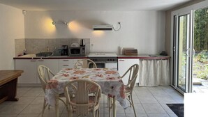 Une cuisine compacte comprenant une table à manger, des chaises, un four à micro-ondes et une machine à café.