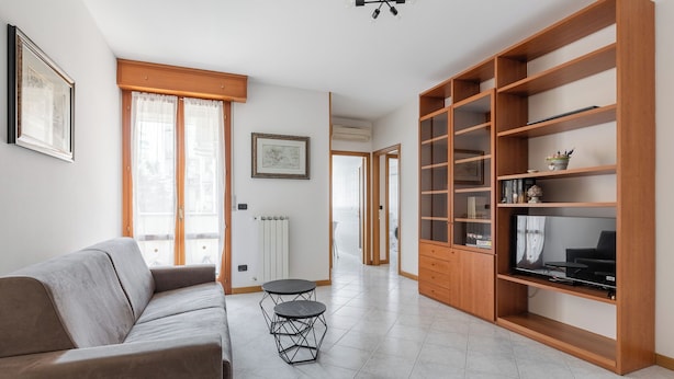 A modern living room with a sofa, a small round table, and a wooden bookshelf. - Bologna Modern Apartment by Wonderful Italy (Bologna)