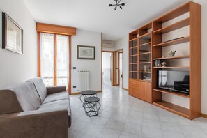 A modern living room with a sofa, a small round table, and a wooden bookshelf. - Bologna Modern Apartment by Wonderful Italy (Bologna)