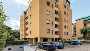 A multi-story residential building with balconies, a parking area, and a small garden area. - Bologna Modern Apartment by Wonderful Italy (Bologna)