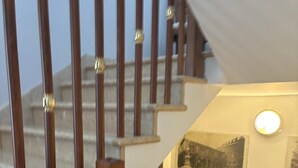 Un escalier en bois avec une rampe et un luminaire fixé au mur.