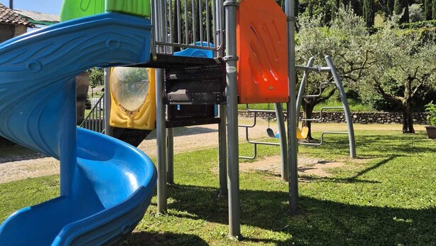 A playground with a blue slide, a green climbing structure, and an orange climbing frame. - Locanda Cà del Ponte (Costermano sul Garda)