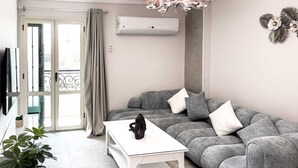 A modern living room with a grey sofa, a white coffee table, and a potted plant. - Xuru Stays I Elegant & Modern 3 BDR Apt. @ Heliopolis (Cairo)