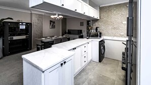 A modern kitchen with white cabinetry, a marble countertop, and a stone backsplash. - Xuru Stays I Elegant & Modern 3 BDR Apt. @ Heliopolis (Cairo)