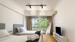 A hotel room with two beds, a TV on a stand, and a window with curtains. - Xuru Stays I The 2bdr Velvet Vibe @ Maadi (Cairo)
