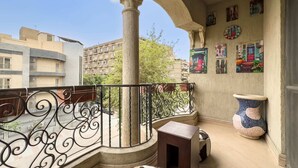 Ein Balkon mit schmiedeeisernem Geländer, einem Blumentopf und einem kleinen Tisch.