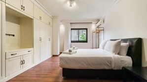 Ein Schlafzimmer mit Bett, Kleiderschrank und einem Fenster mit Blick auf Grünflächen.