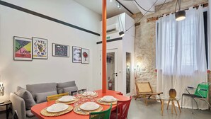 Un comedor con una mesa roja preparada para cuatro personas, rodeado de sillas coloridas.