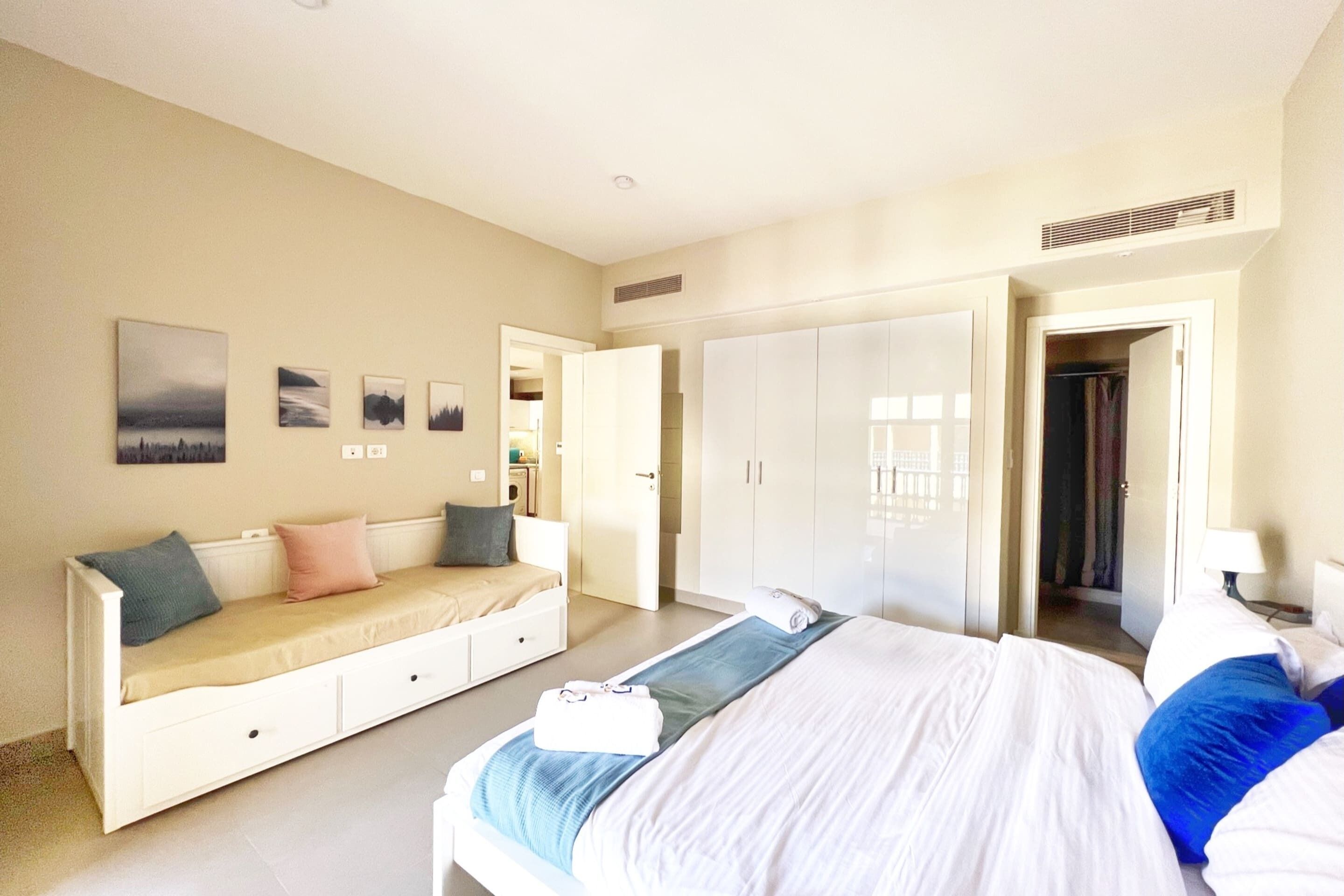 Een slaapkamer met een bed, een slaapbank, een garderobe en een spiegel.