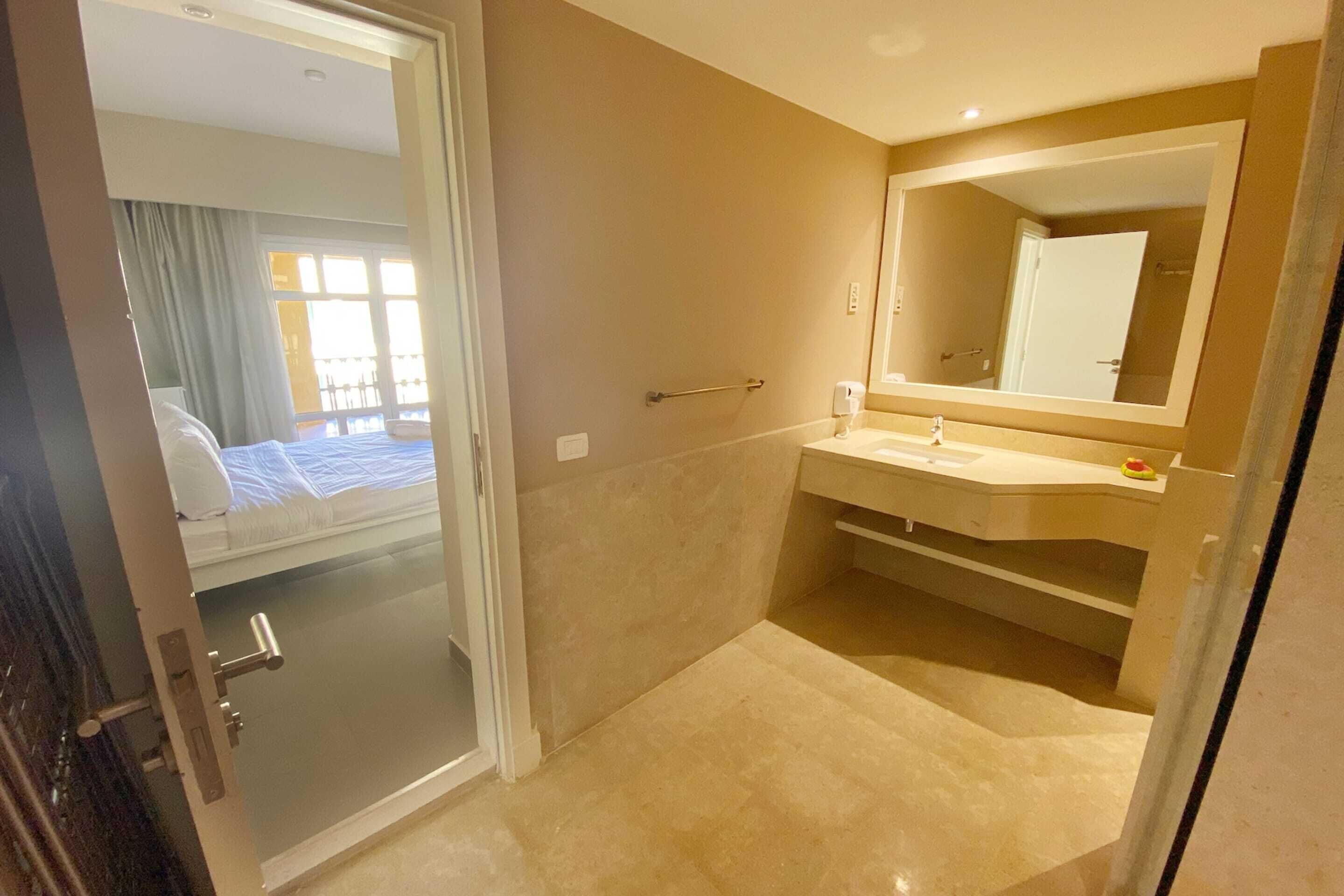Un baño de hotel con un espejo grande, un lavabo y una zona de ducha.