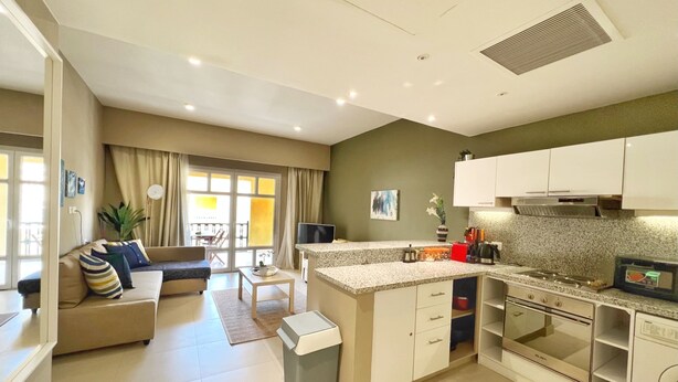 A modern kitchen with white cabinets, a built-in oven, and a granite countertop. - Xuru Stays I Minimal & Central 1bdr Apt. @ Abu Tig Marina (El Gouna)