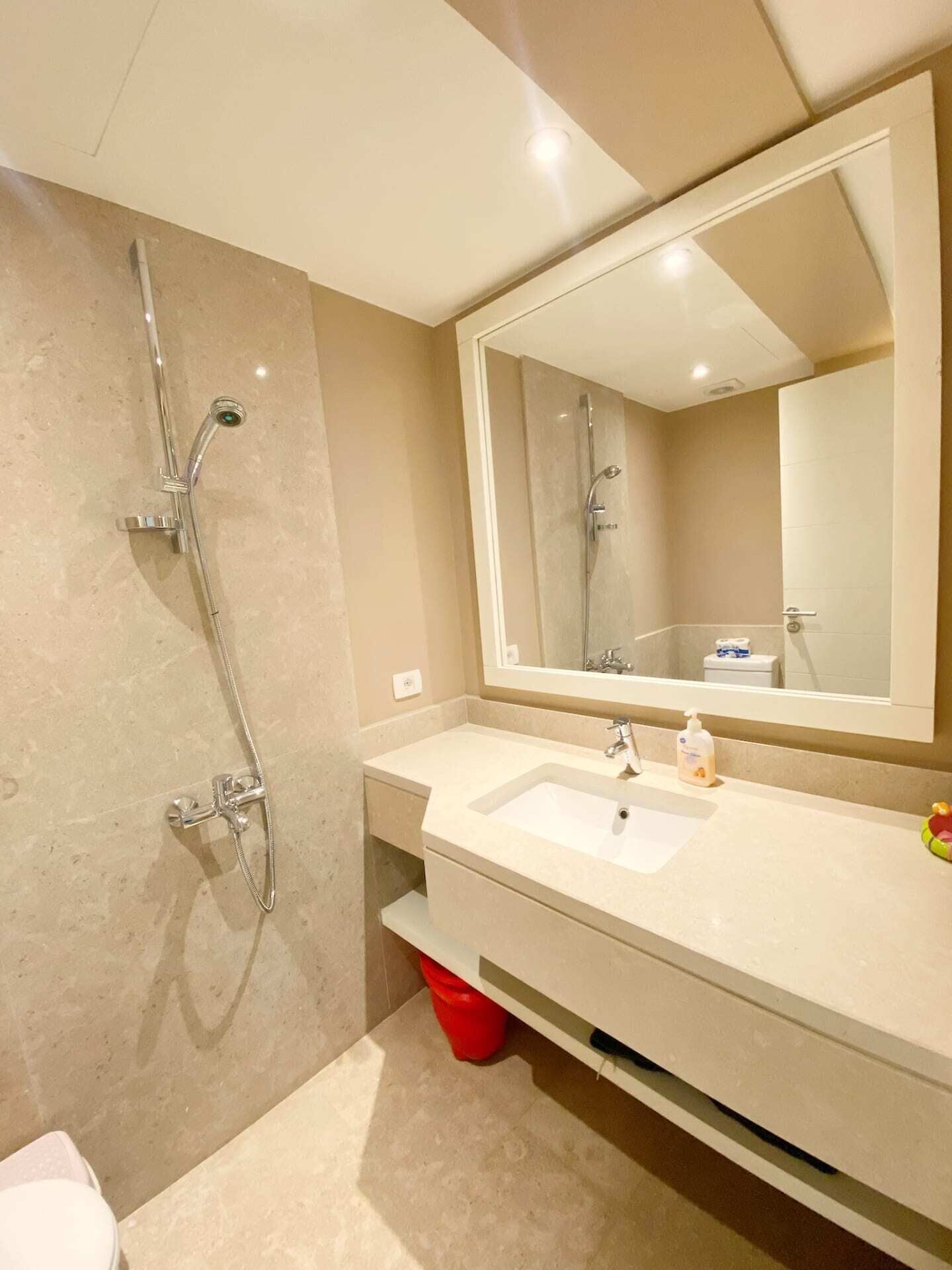 A modern bathroom with a large mirror, a sink, and a shower.