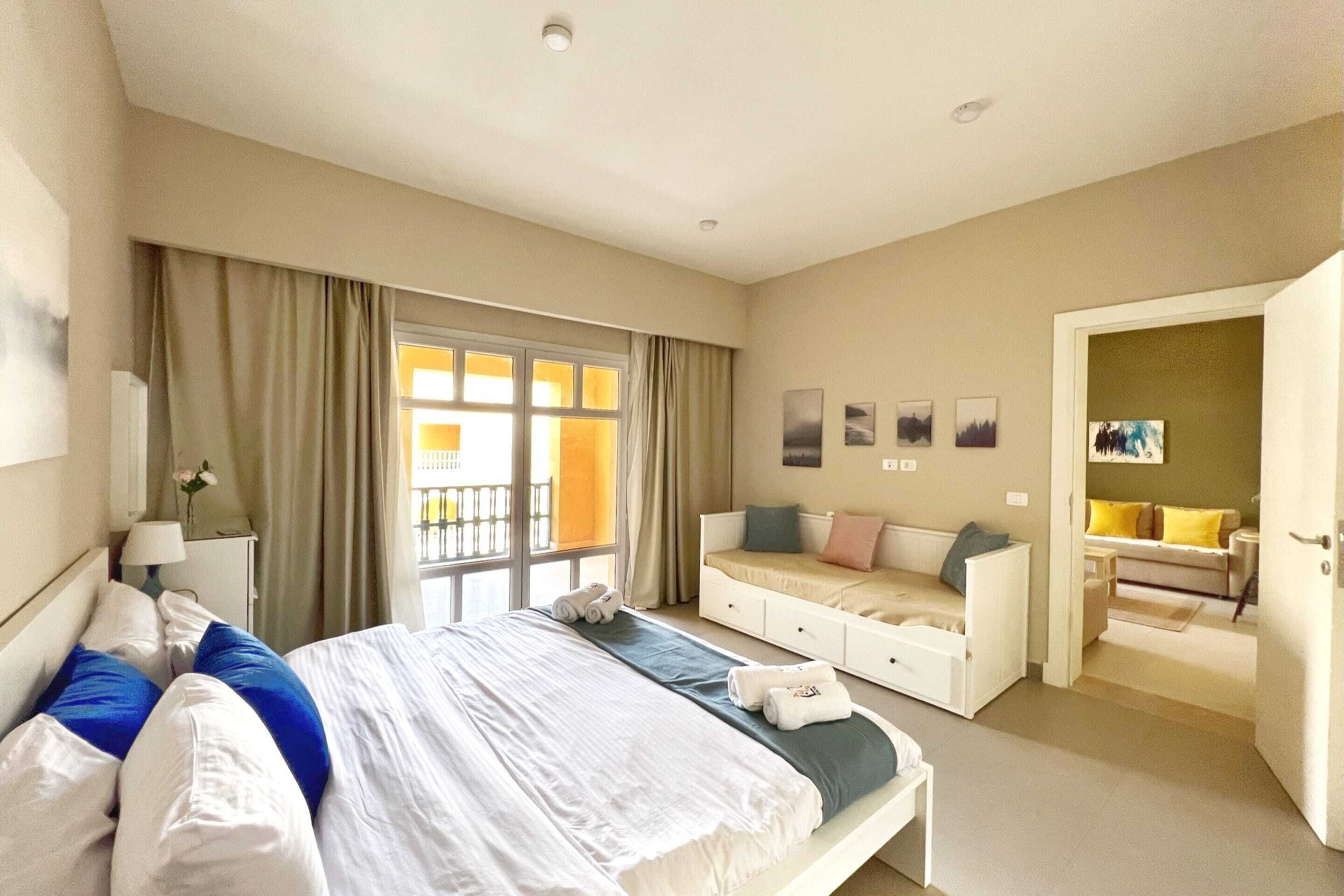 A modern hotel room with a large bed, a seating area, and a view of the outdoors.