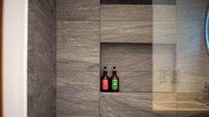 A bathroom with a tiled wall and two bottles of shampoo in a recessed shelf. - Stylish Studio in Zazil-Ha - Rooftop Pool (Playa del Carmen)