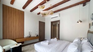 Un dormitorio moderno con una cama grande, cabecera de madera, un banco y una lámpara colgante.