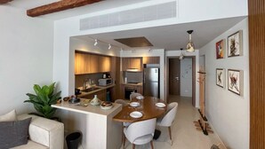 Una cocina moderna con armarios de madera, una isla central y un comedor con sillas.