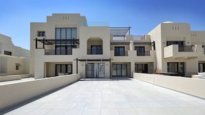 Un moderno edificio residencial de varios pisos, con balcones, ventanas amplias y un amplio patio.
