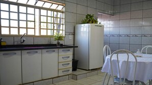 A compact kitchen with a window, a refrigerator, a sink, and a dining table with chairs.
