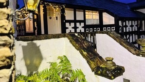 A traditional half-timbered house with a white exterior, a wooden staircase, and a lantern. - Pentre Cerrig Country House (Mold)