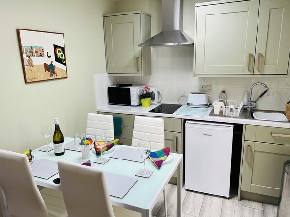 A modern kitchen with white cabinets, a microwave, a sink, and a dishwasher. - Pentre Cerrig Country House (Mold)