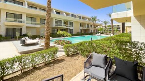 A hotel with a pool, outdoor seating, and a well-maintained garden. - Refreshed & Uplifted 2 BDR @ G Cribs (El Gouna)