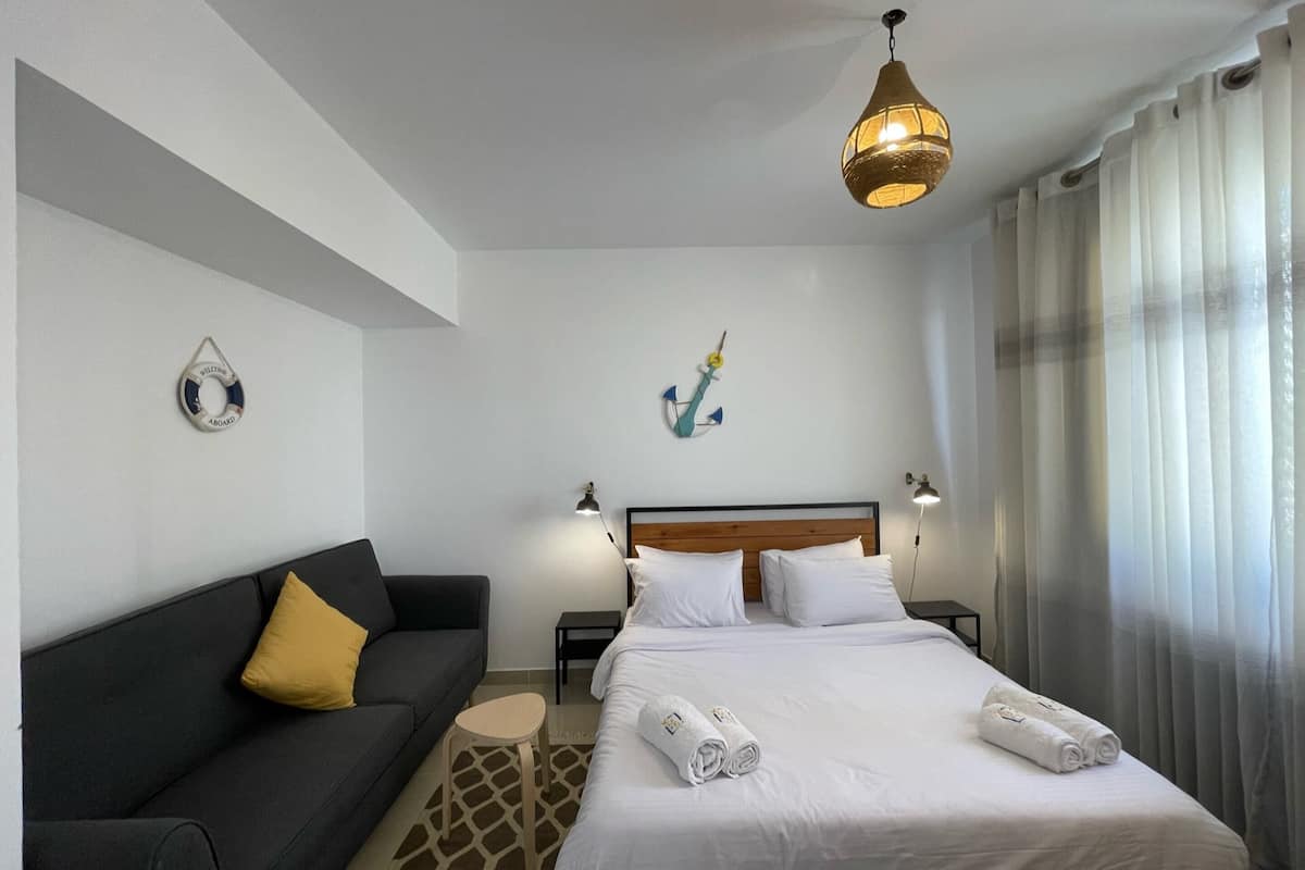 Een hotelkamer met een bed, een bank, een kleine tafel en een wandlamp.
