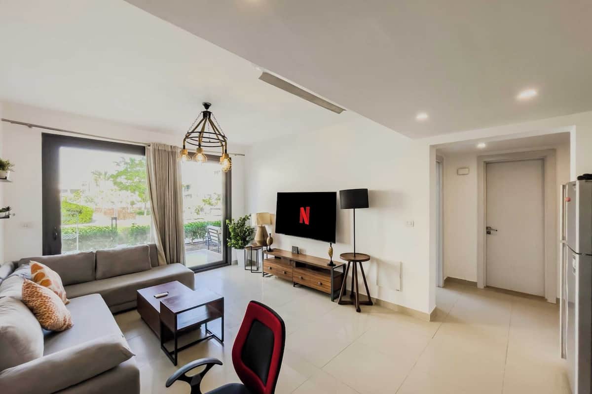 Een moderne woonkamer met een bank, een salontafel, een televisie en een eethoek.