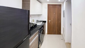 A compact kitchen with a black refrigerator, a washing machine, and a wooden door. - Refreshed & Uplifted 2 BDR @ G Cribs (El Gouna)