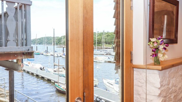 Blick aus einem Zimmer mit einer Holztür, die zu einem Yachthafen mit vertäuten Booten führt.