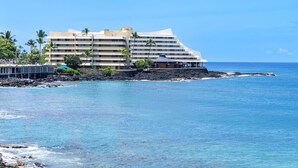 A beachfront hotel with multiple balconies, a pool, and a view of the ocean.