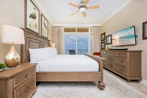 A bedroom with a bed, a ceiling fan, a TV, a dresser, and a balcony with curtains. - Phoenix Orange Beach 603 3 Bedroom Condo (Orange Beach)