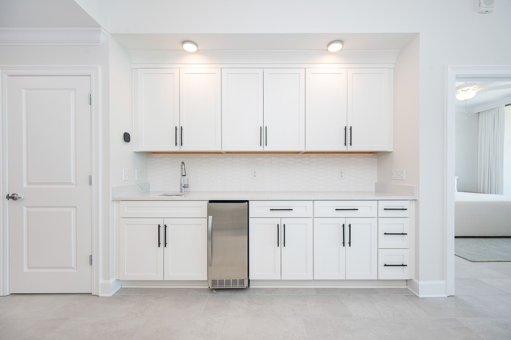 A modern kitchen with white cabinets, a stainless steel dishwasher, and recessed lighting.