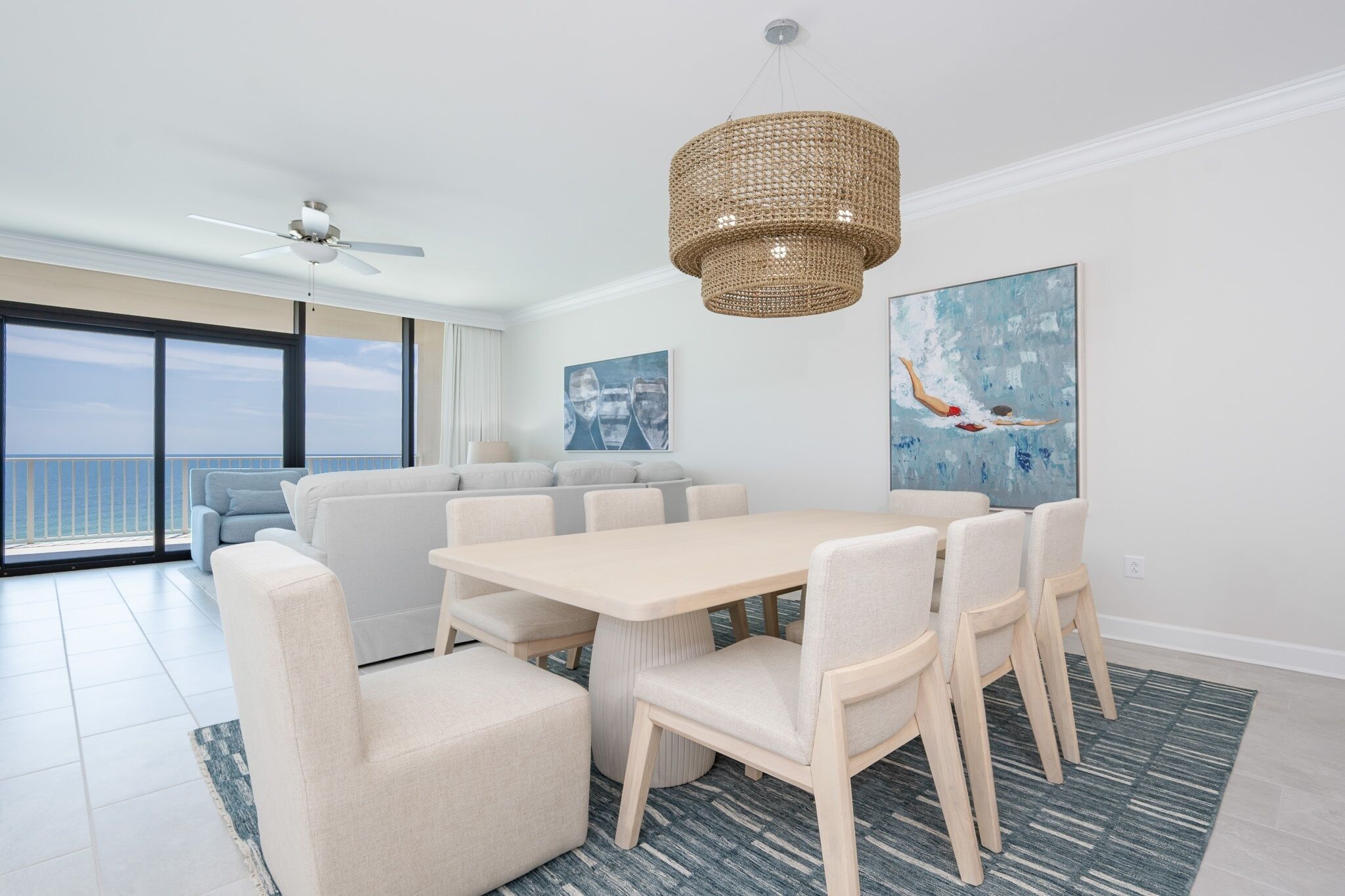 Una sala moderna con una mesa de comedor, sofás y un amplio ventanal con vistas a un balcón.