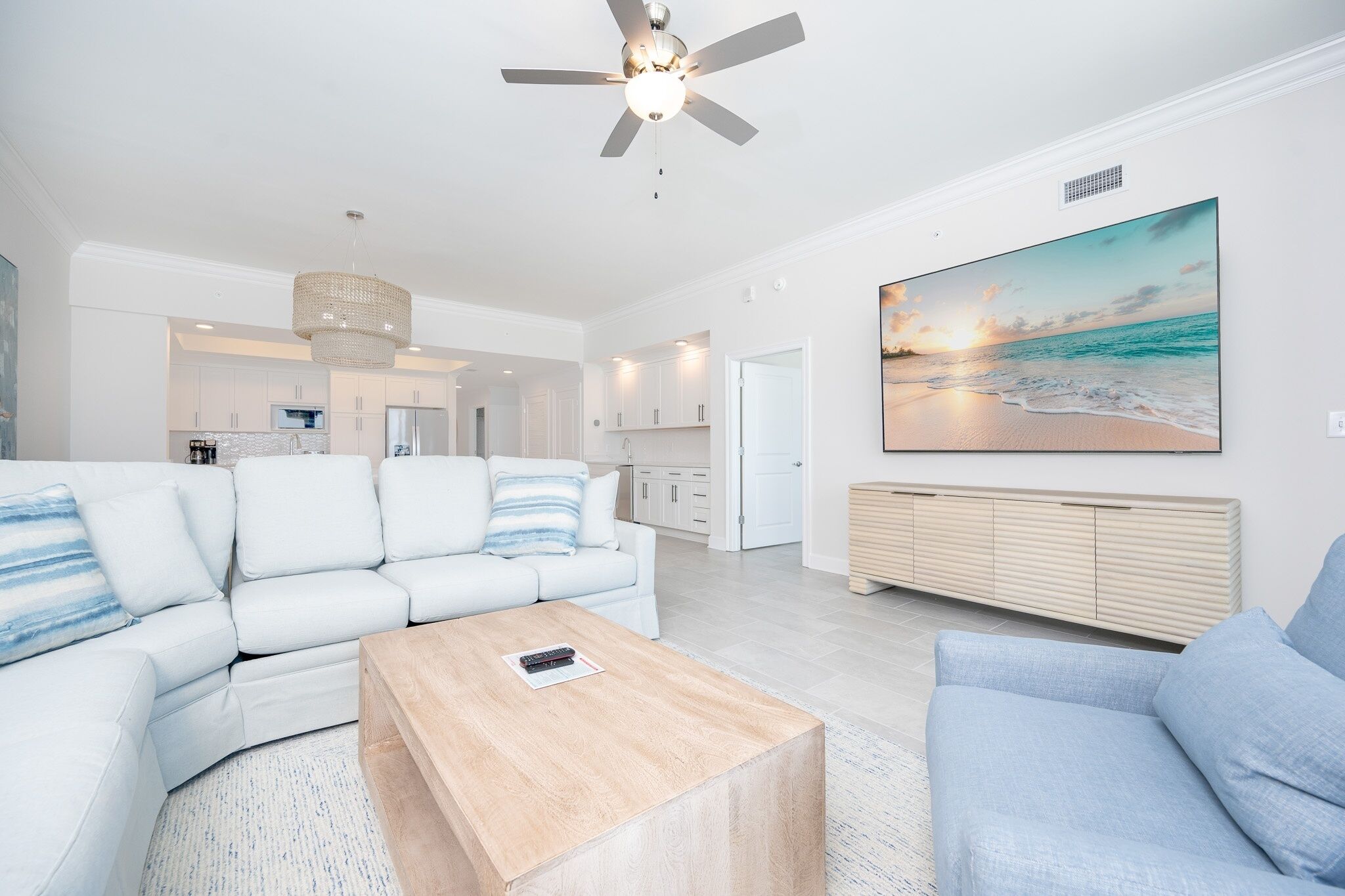 Un soggiorno moderno con un divano bianco, un tavolino in legno e un grande quadro raffigurante una spiaggia.