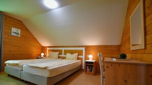 A bedroom with two beds, a wooden headboard, a nightstand with a lamp, and a small bookshelf. - Doppelhaushaelfte in Hasselfelde (Oberharz am Brocken)