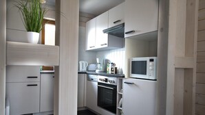 A compact kitchen with white cabinets, a microwave, an oven, and a coffee maker. - Doppelhaushaelfte in Hasselfelde (Oberharz am Brocken)