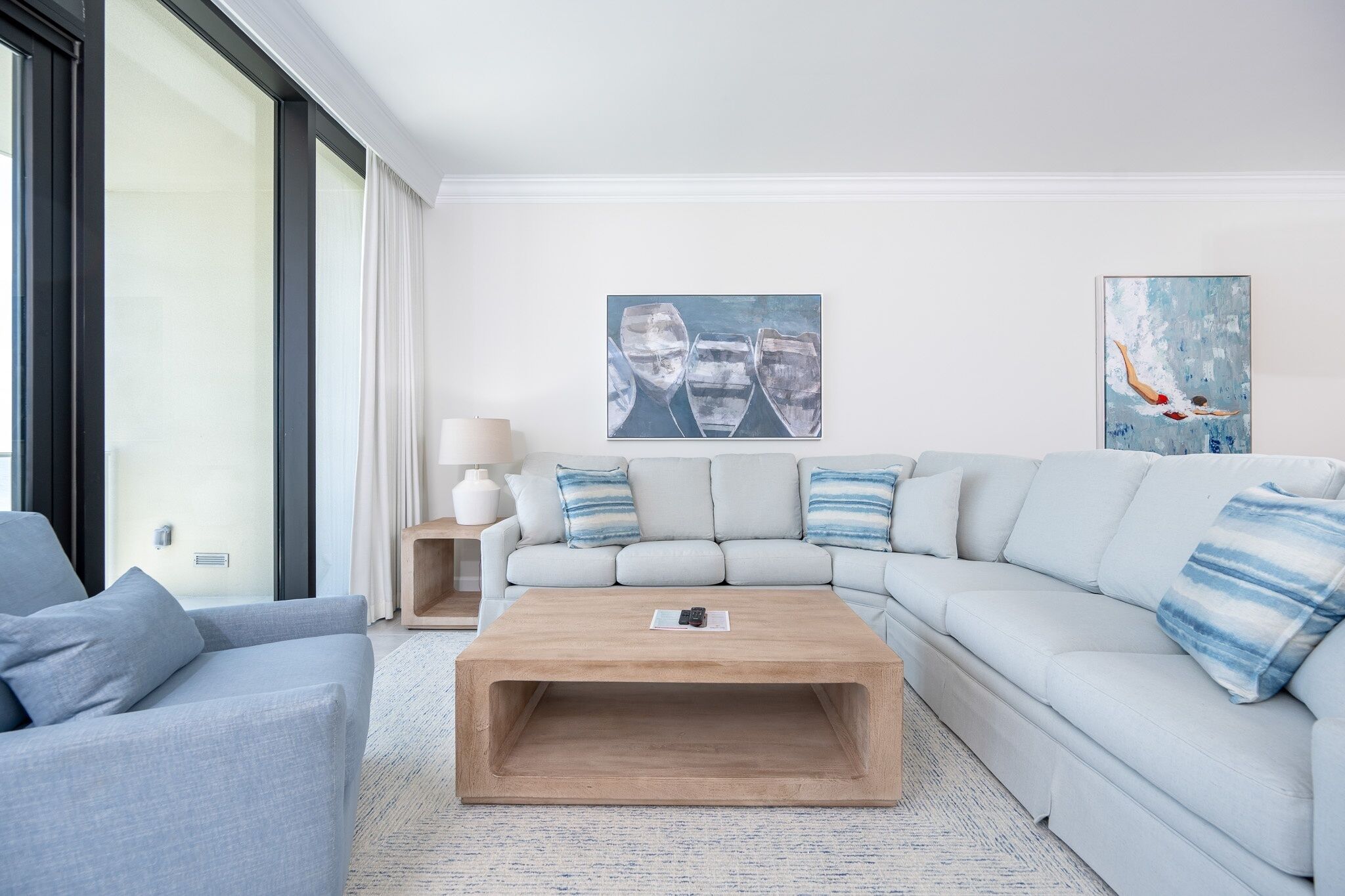 A modern living room with a light grey sofa, a wooden coffee table, and two paintings on the wall.