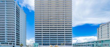 Un hotel moderno con una torre central y dos alas laterales, conectadas por una pasarela de madera.