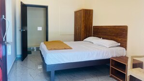 A bedroom with a bed, wooden wardrobe, and a small wooden table. - Aashira Residency (Mayiladuthurai)