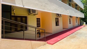 A multi-story building with a red carpet leading to the entrance, outdoor air conditioning units, and a staircase with metal railings. - Aashira Residency (Mayiladuthurai)